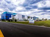 Blue Origin manufacturing facility exterior with large blue facade, landscaped grounds, and industrial coating system.